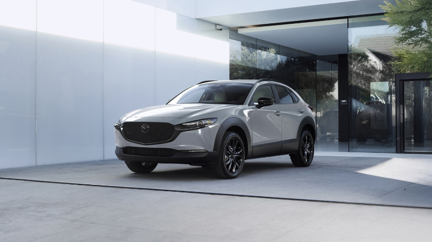 A white Mazda CX-30 parked in front of a building.