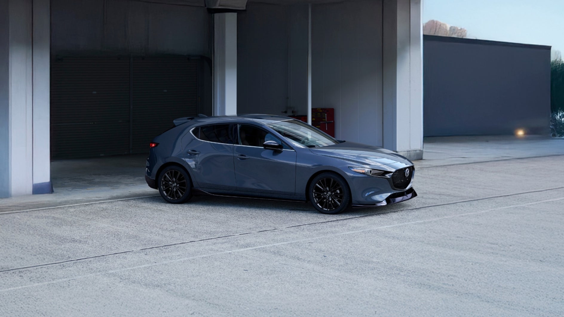  A blue Mazda3 Hatchback leaving a parking garage.
