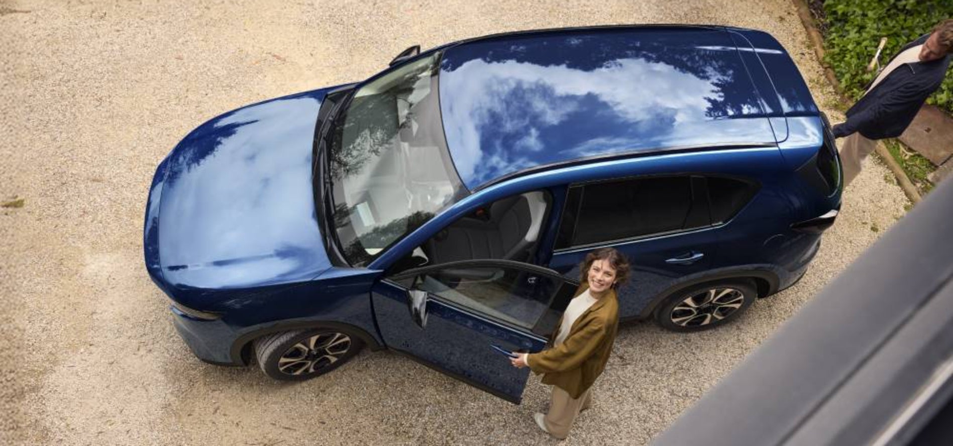 An overheard view of a couple getting into a blue Mazda CX-5.