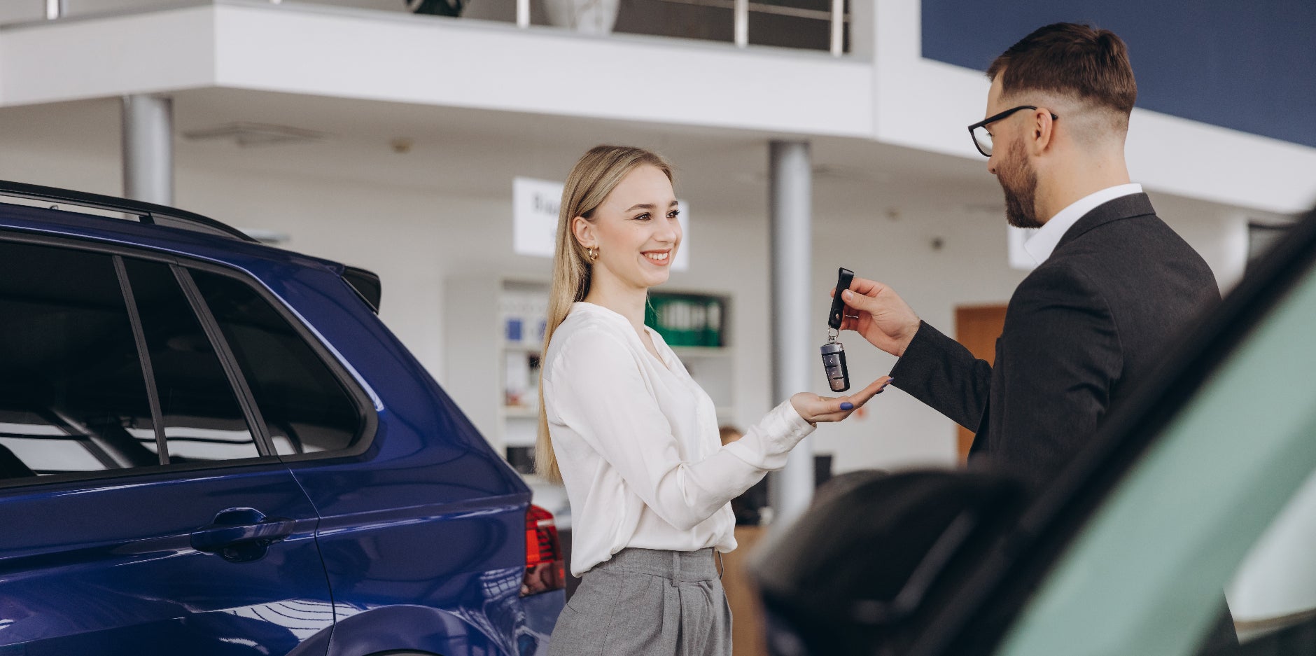 Happy woman getting handed the keys to her used vehicle